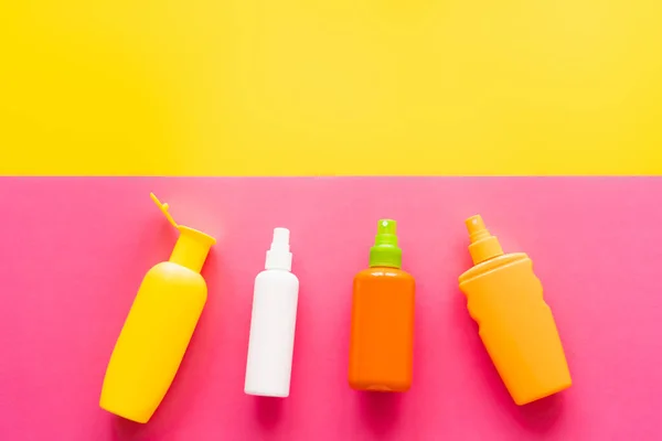 Top view of bottles of sunscreens on yellow and pink background — Stock Photo