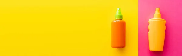 Top view of sunblock in bottles on pink and yellow background, banner — Stock Photo