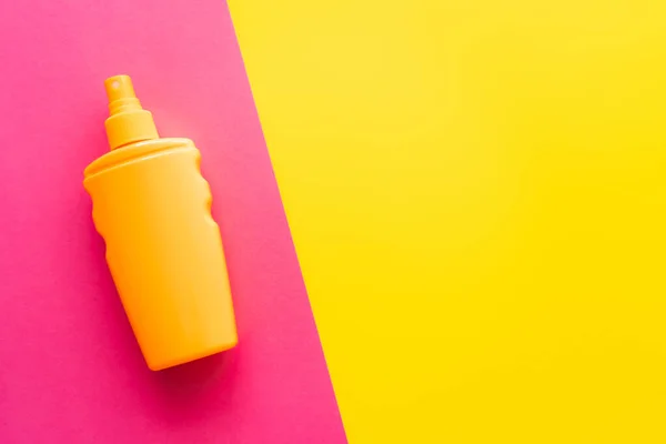 Top view of sunblock on pink and yellow background — Stock Photo