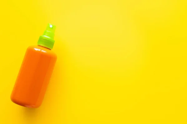 Draufsicht auf eine Flasche Sonnencreme auf gelber Oberfläche — Stockfoto