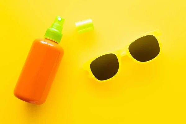 Top view of sunscreen and sunglasses on yellow surface — Stock Photo