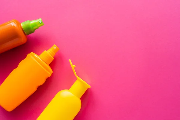 Draufsicht auf Sonnenschutzmittel in Flaschen auf rosa Oberfläche mit Kopierraum — Stockfoto