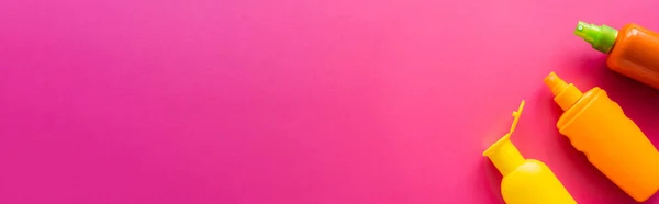 Vista superior de bloqueador solar en botellas en superficie rosa, banner - foto de stock