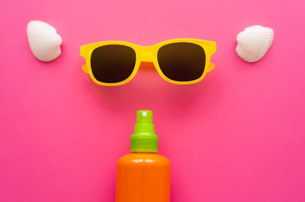 Top view of sunscreen near sunglasses and seashells on pink surface — Stock Photo