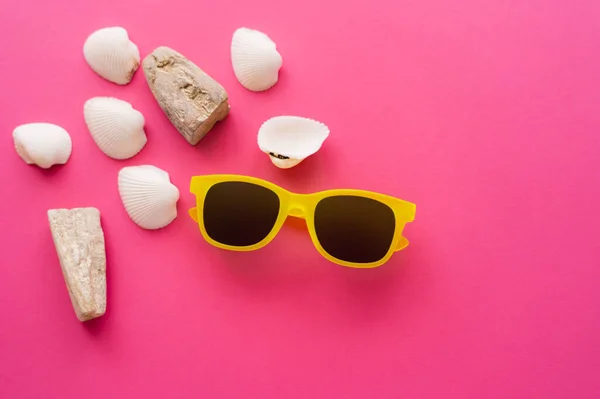 Top view of sunglasses and seashells on pink background — Stock Photo