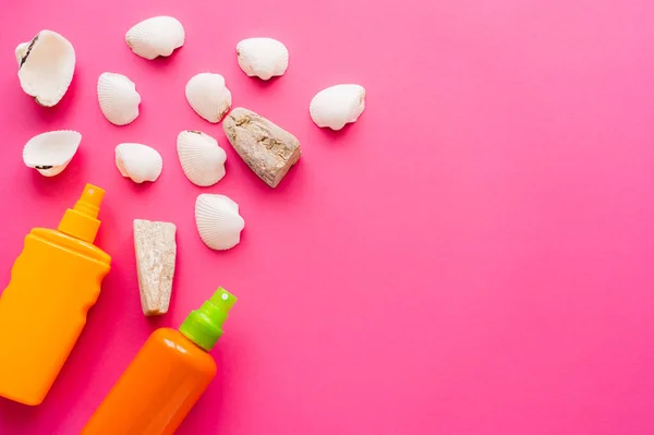 Top view of seashells and sunscreens on pink background — Stock Photo
