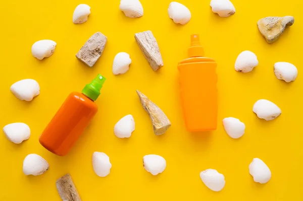 Top view of seashells and stones near sunscreens on yellow background — Stock Photo