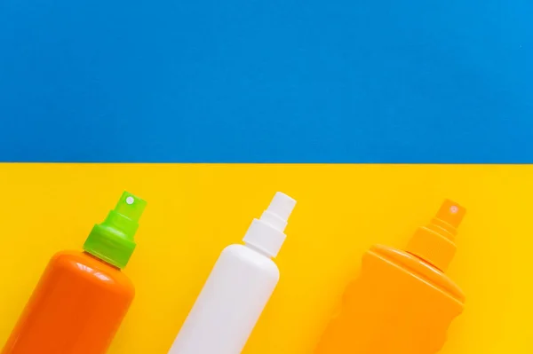 Top view of sunscreens on yellow and blue background — Stock Photo