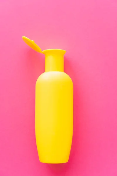 Vue du dessus de la bouteille jaune de crème solaire sur la surface rose — Photo de stock