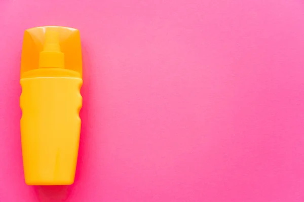 Draufsicht auf orangefarbene Flasche Sonnencreme auf rosa Oberfläche — Stockfoto