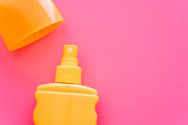 Vista superior del protector solar y la tapa en la superficie rosa — Stock Photo
