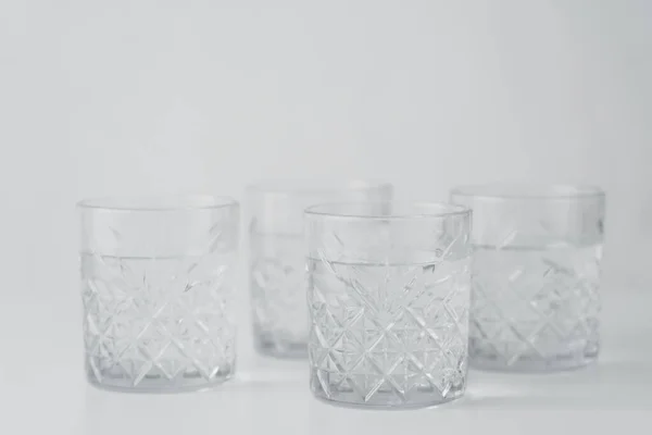 Occhiali sfaccettati con acqua fresca annuncio chiaro su sfondo grigio — Foto stock