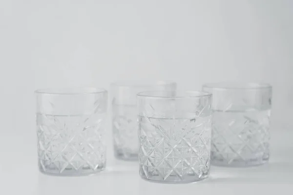 Verres à facettes avec de l'eau claire et fraîche sur fond gris — Photo de stock