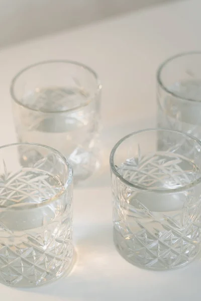Vue rapprochée des verres à facettes avec de l'eau douce sur fond gris — Photo de stock
