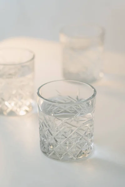 Vista de perto de vidro de cristal com água doce sobre fundo cinza desfocado — Fotografia de Stock