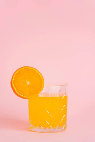 Vidro de suco cítrico puro com fatia de laranja fresca no fundo rosa — Fotografia de Stock