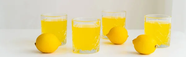 Glasses with fresh citrus tonic near whole lemons on white surface and grey background, banner — Stock Photo