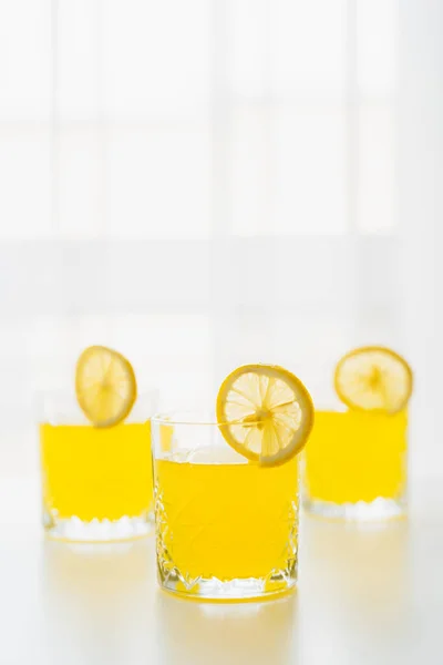 Vasos con refrescante tónico cítrico y rodajas de limón sobre fondo blanco con espacio para copiar - foto de stock
