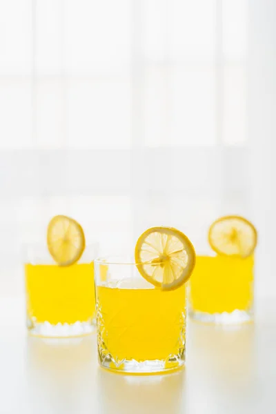 Verres avec tonique d'agrumes rafraîchissant et tranches de citron sur fond blanc avec espace de copie — Photo de stock