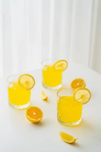 Refreshing citrus drink and lemon slices on white tabletop and blurred background — Stock Photo