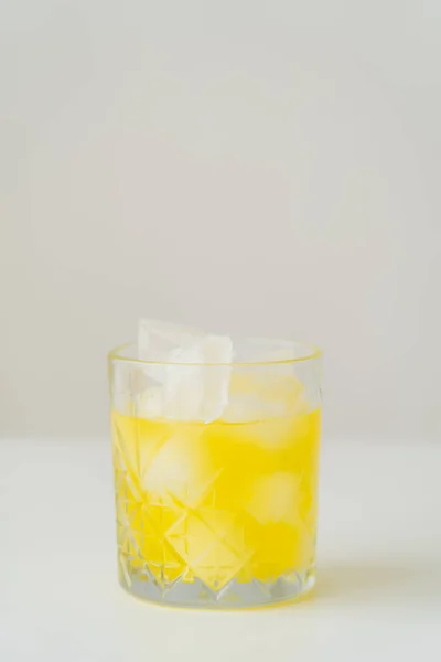 Glass with fresh citrus tonic and ice cubes on grey background with copy space — Stock Photo