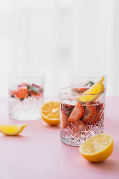 Tonic water with lemon and strawberries on blurred background with white copy space — Stock Photo