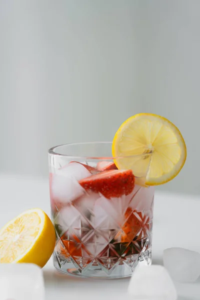 Tónico frío con fresas frescas y rodaja de limón en la superficie blanca aislada en gris - foto de stock