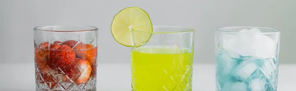 Citrus juice near strawberry tonic and glass with ice on grey background, banner — Stock Photo