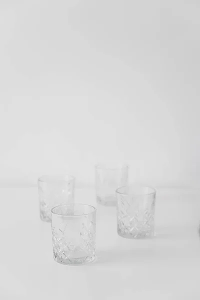 Quatro vidros facetados vazios em fundo cinza com espaço de cópia — Fotografia de Stock