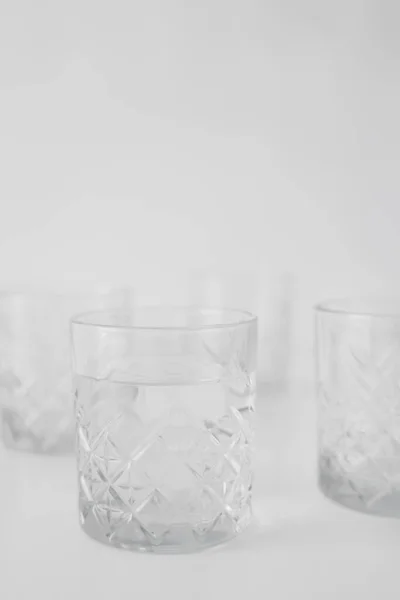 Селективное фокусирование прозрачного стекла с водой на сером размытом фоне — стоковое фото