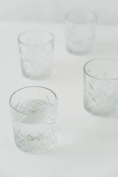 Vue grand angle des verres avec de l'eau propre sur fond gris flou — Photo de stock