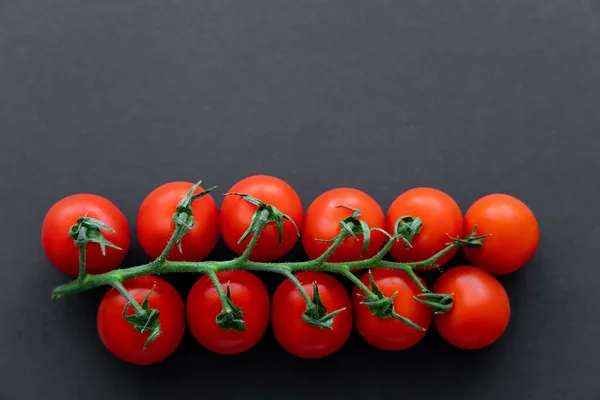 Vista superior de tomates cereja no ramo no fundo preto — Fotografia de Stock