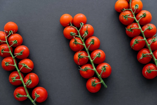 Draufsicht auf Bio-Kirschtomaten auf Zweigen auf schwarzem Hintergrund — Stockfoto