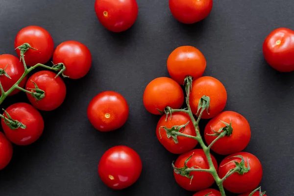 Vista superior de tomates cereja orgânicos em ramos no fundo preto — Fotografia de Stock