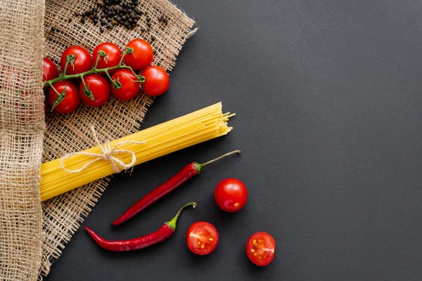 Vue du dessus des pâtes non cuites et des légumes frais sur sac sur fond noir — Photo de stock