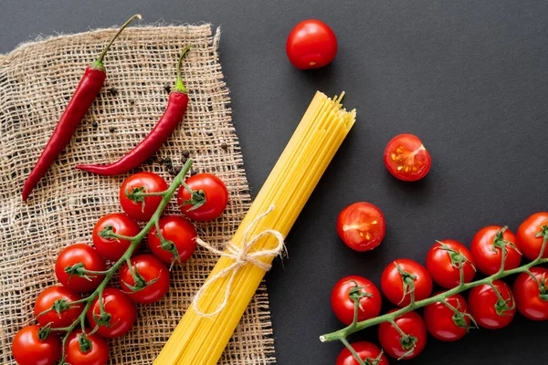 Vue du dessus des spaghettis crus et des légumes mûrs sur sac sur fond noir — Photo de stock