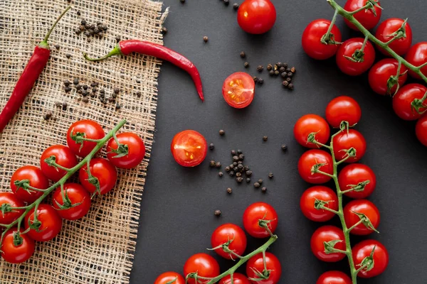 Vista superior de granos de pimienta cerca de verduras frescas orgánicas sobre tela de saco sobre fondo negro - foto de stock