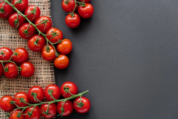 Top view of fresh cherry tomatoes on sackcloth on black background — Stock Photo