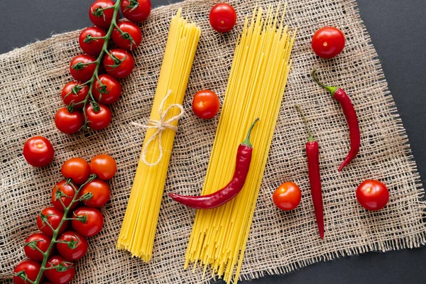 Vista dall'alto di verdure fresche e pasta cruda su sacco su fondo nero — Foto stock