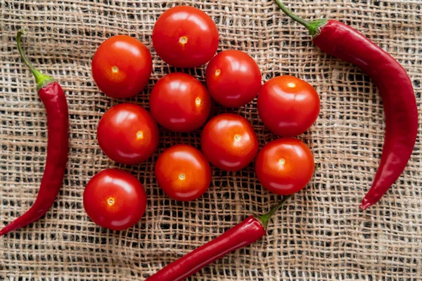 Blick von oben auf Chilischoten und Kirschtomaten auf Sacktuch — Stockfoto