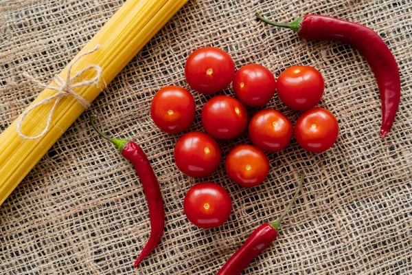 Top view of raw spaghetti and fresh vegetables on sackcloth — Stock Photo