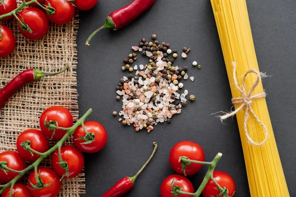 Vista dall'alto di verdure fresche vicino al sale e pasta cruda su sacco su sfondo nero — Foto stock