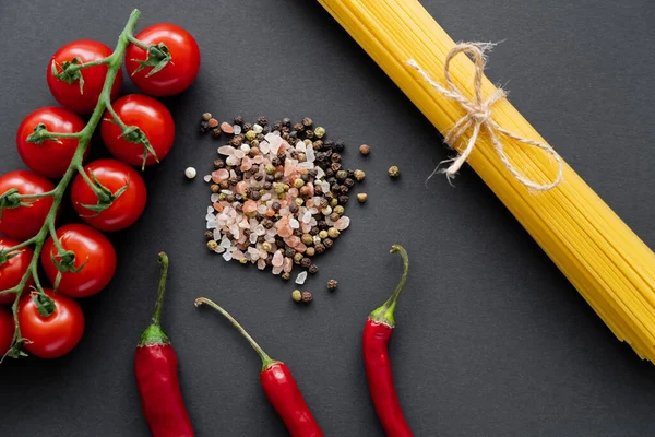 Draufsicht auf reifes Gemüse in der Nähe von Gewürzen und ungekochten Spaghetti auf schwarzem Hintergrund — Stockfoto