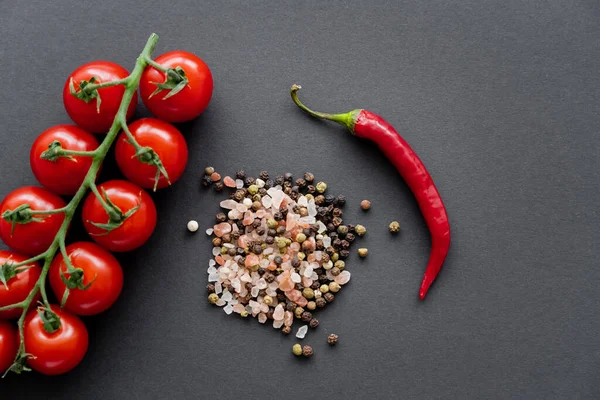 Top view of cherry tomatoes near chili pepper and spices on black background — Stock Photo