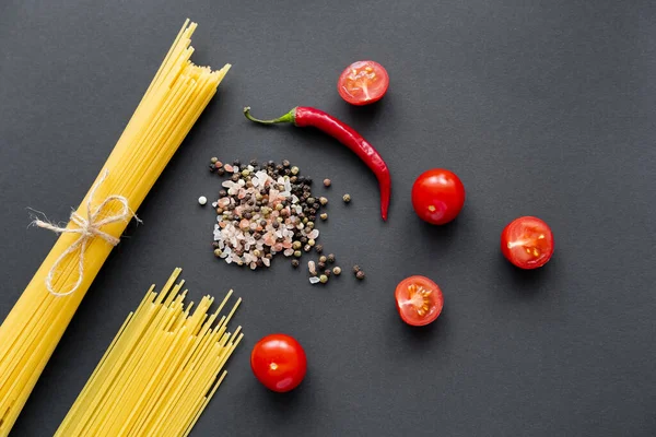 Vista superior de vegetais orgânicos perto de especiarias e massas não cozidas no fundo preto — Fotografia de Stock