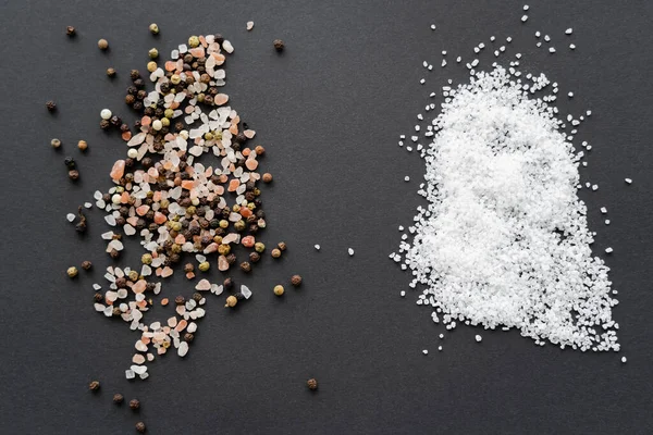 Vue du dessus des grains de poivre et du sel sur fond noir — Photo de stock