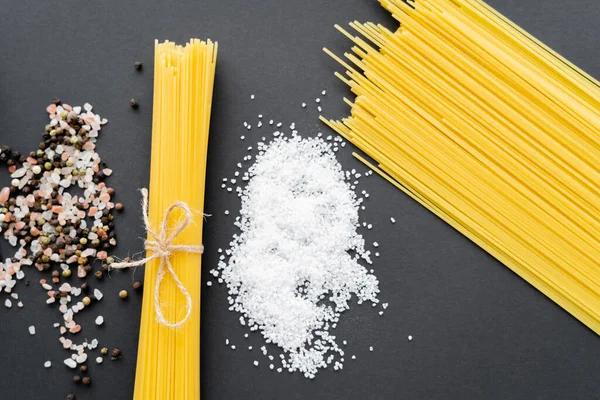 Vista dall'alto di sale vicino spezie e pasta cruda su sfondo nero — Foto stock