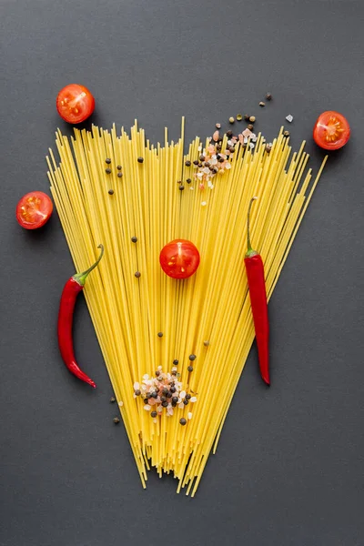 Poser à plat avec des légumes rouges et des épices sur des spaghettis sur fond noir — Photo de stock
