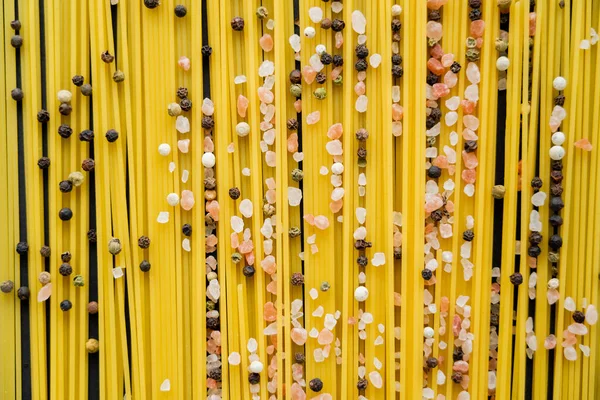 Top view of spices on raw spaghetti on black background — Stock Photo