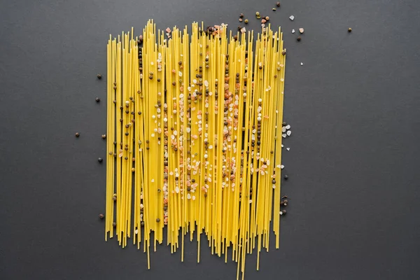 Top view of spices and uncooked pasta on black background — Stock Photo